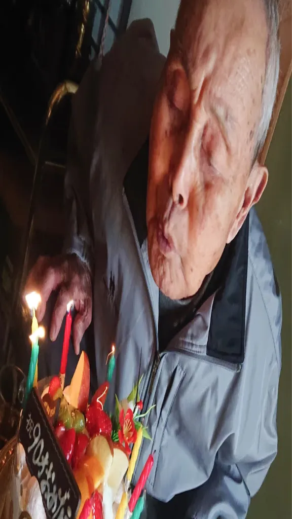 誕生日ケーキのろうそくを消す高齢の男性
