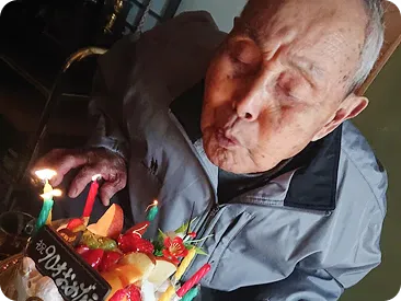 誕生日ケーキのろうそくを吹き消す高齢の男性