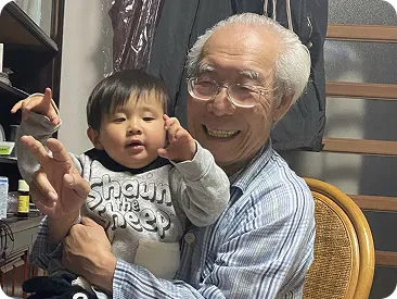 孫を膝に乗せて微笑む祖父