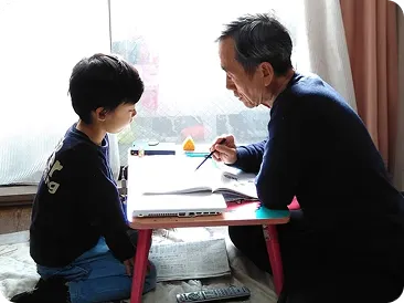 机に向かう孫を見守る祖父